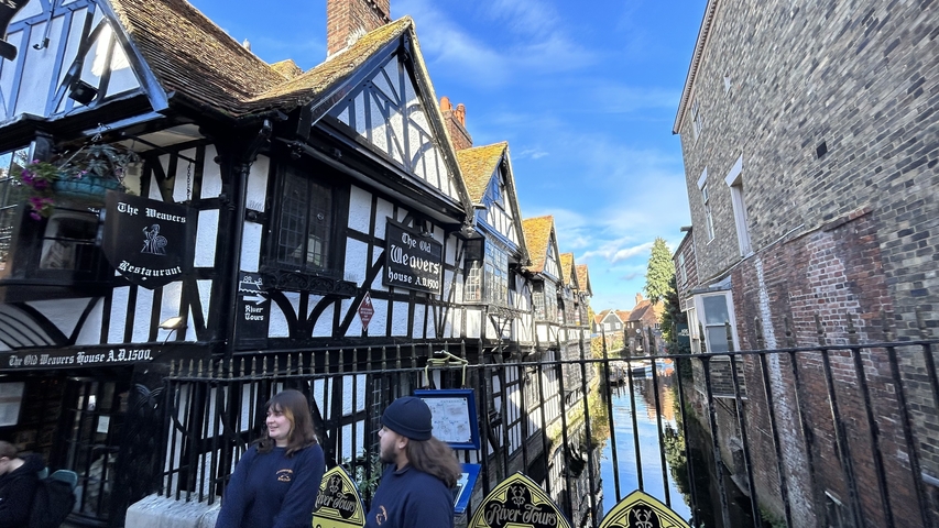       Two people walking near a historic Tudor-style building.
  
