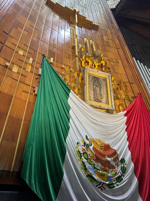 Large Mexican flag and religious icon indoors.