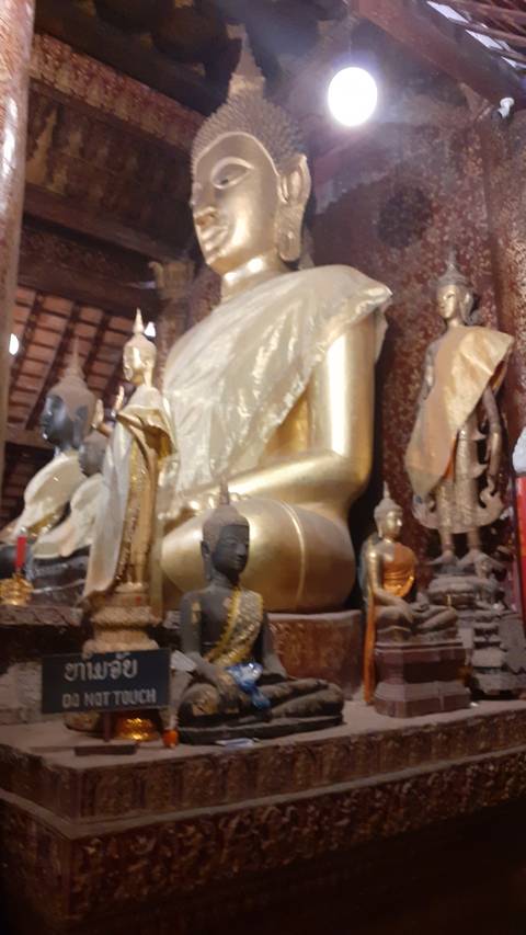       Golden reclining Buddha statue surrounded by other sculptures.
  