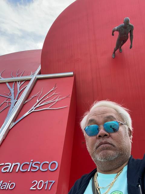 Person in front of a red wall with statue above.