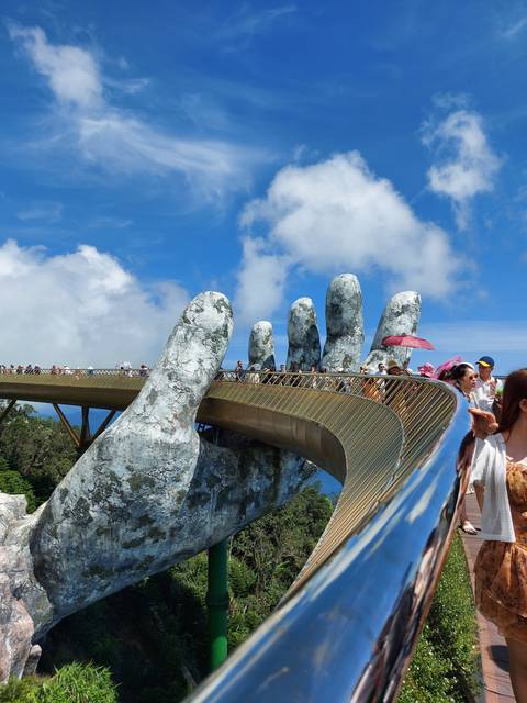 Giant hand bridge on a mountain with visitors.