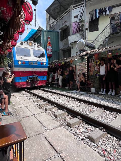       Train passing through a narrow street with buildings.
  