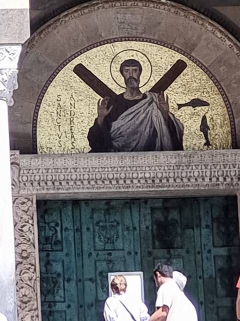 Mosaic religious artwork with people nearby.