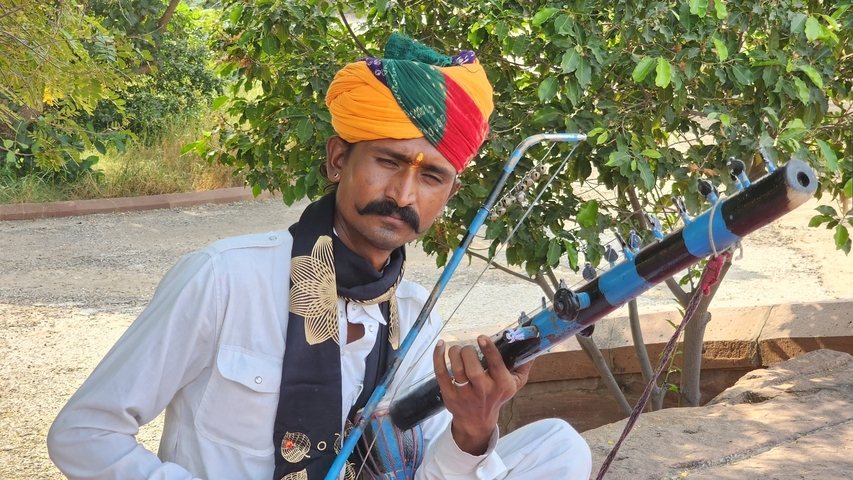 Man in traditional attire playing a string instrument.