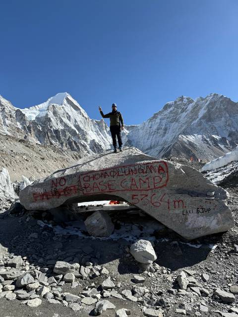 Hiker next to an Everest Base Camp rock sign.