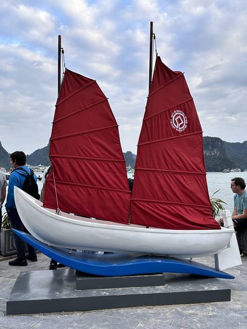       Small model of a boat with red sails on display.
  
