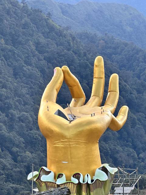       Close-up view of a large golden hand sculpture.
  