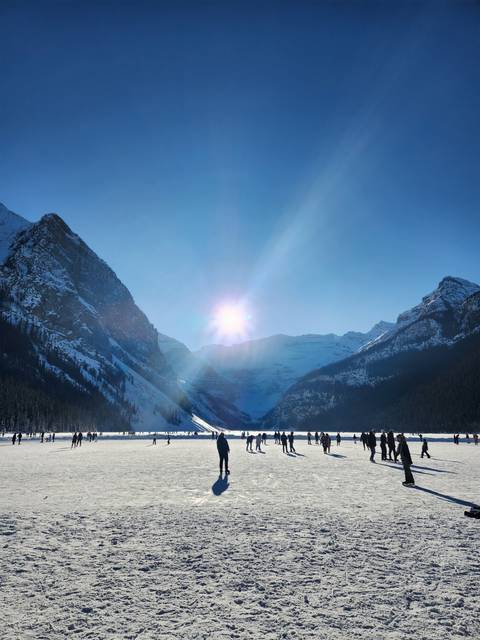 People on a frozen lake with mountains.