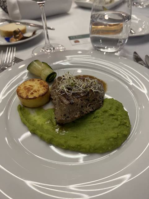 Gourmet dish with green puree, steak, and vegetables on a plate.