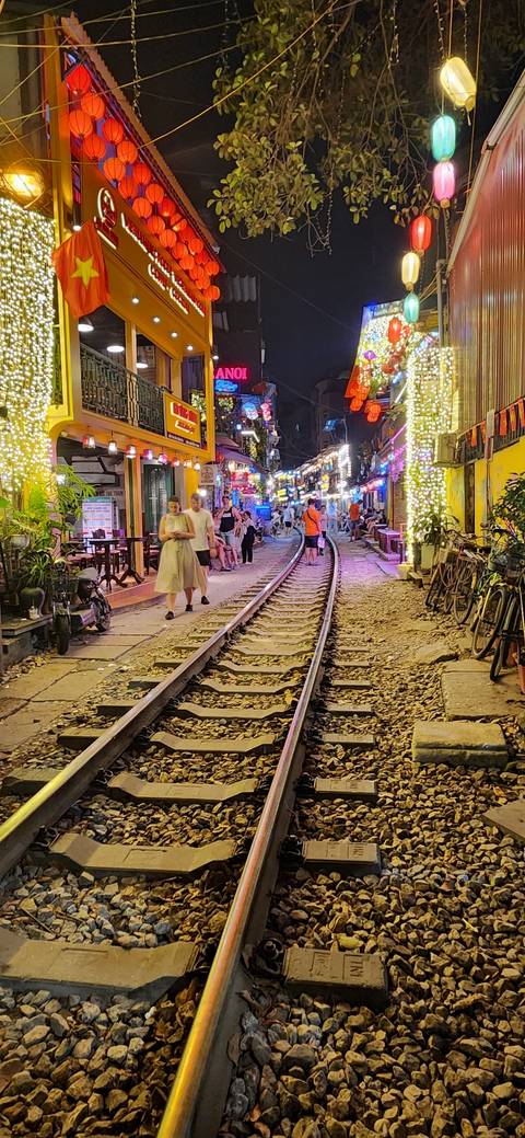 Night scene with train tracks through a busy market street.