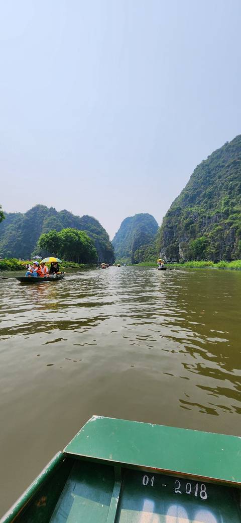       Boats on a river between lush mountains.
  