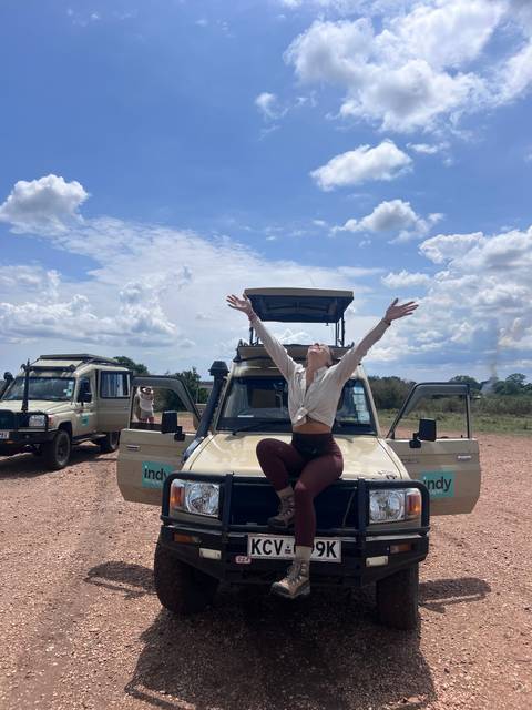       Woman joyfully posing on a safari vehicle.
  