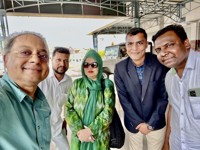 Group selfie with people smiling indoors.