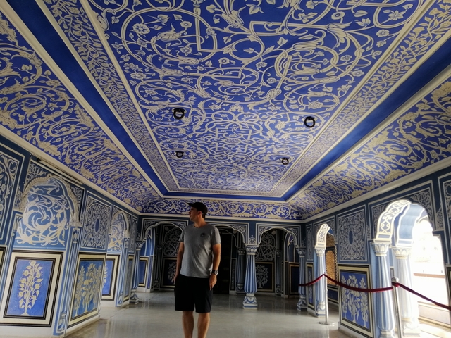 Person standing in a vibrant blue ornate room.