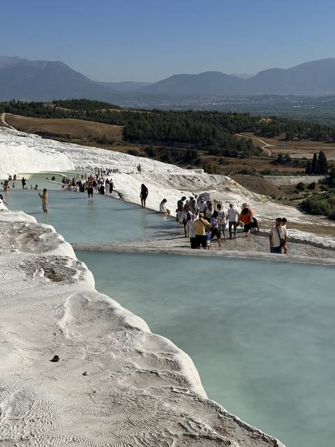       Natural thermal pool with people enjoying a view.
  