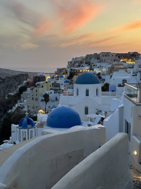       Sunset over white-washed buildings with blue domes.
  