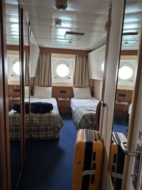       Interior of a cabin with twin beds and a round window.
  