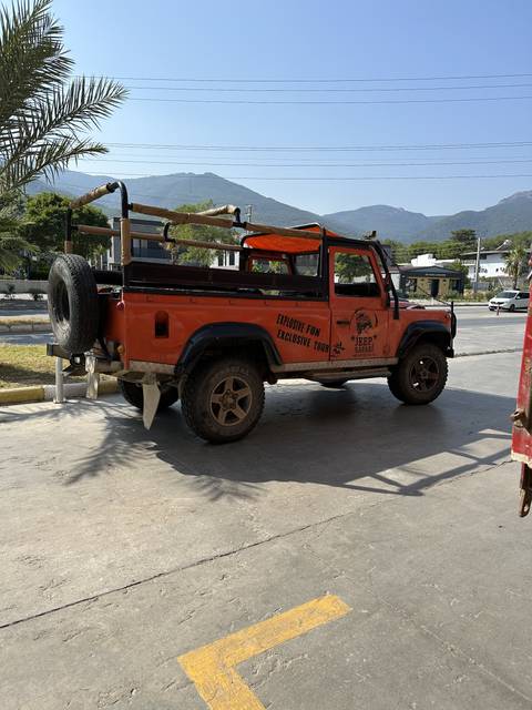       Orange jeep parked on concrete with electrical wires in the background.
  