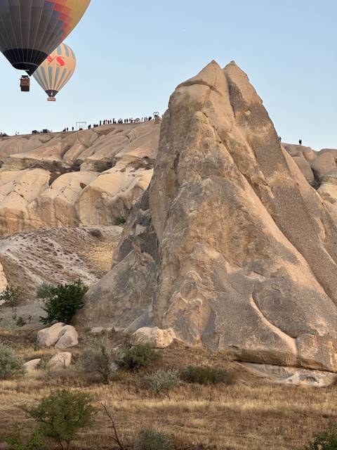       Large rock formations with balloons in the background.
  