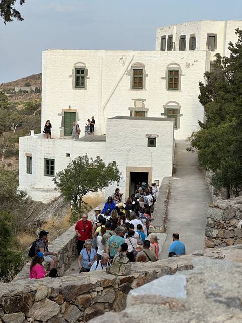       People gathering outside a white building.
  