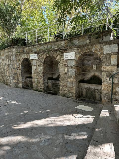       Stone fountain with signs in a shaded area.
  
