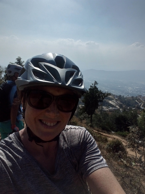 Cyclist in a helmet overlooking a scenic landscape.
