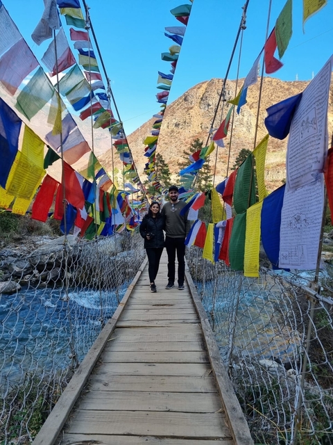      Couple on a bridge with colorful prayer flags.
  