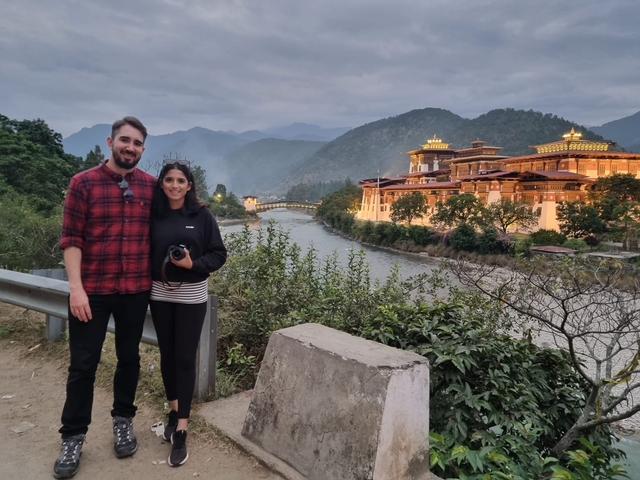       Couple posing with Punakha Dzong in the background.
  
