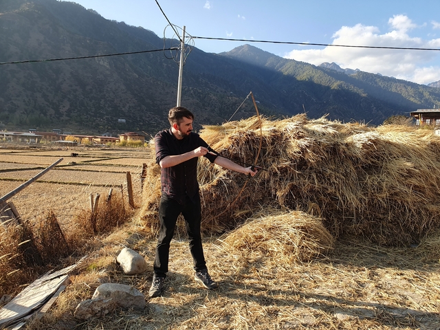       Man practicing archery in a rural setting.
  
