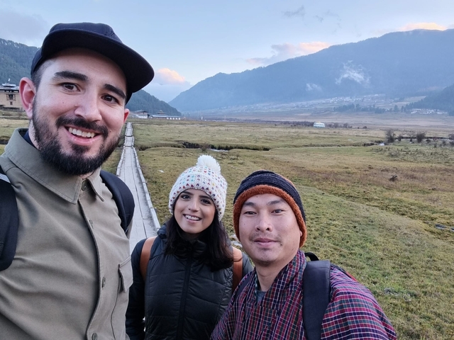       Three friends standing together with winter hats in a valley.
  