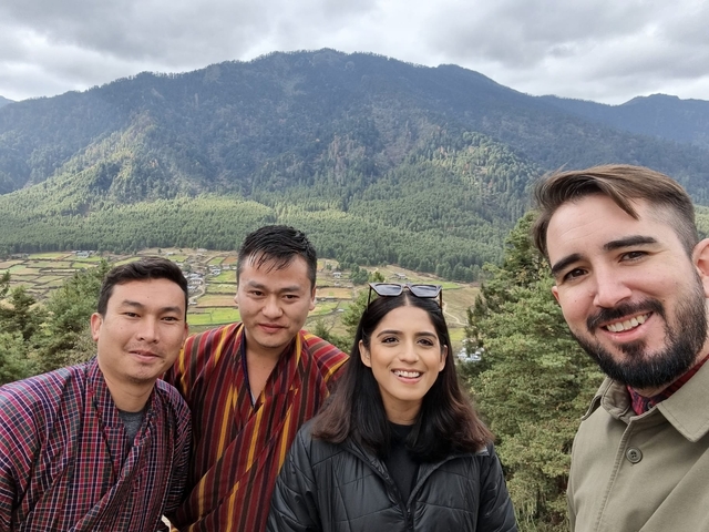       Group posing on a hill with trees and fields below.
  