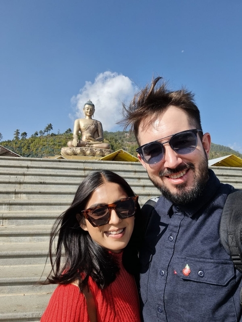       Couple posing in front of a giant Buddha statue.
  