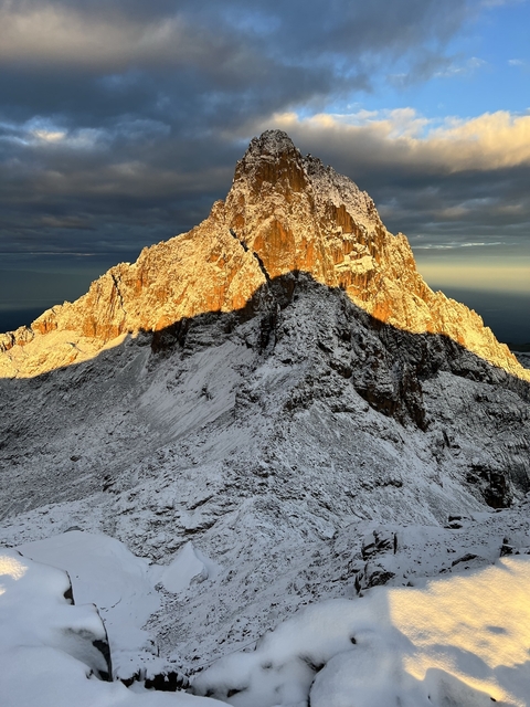       Snow-covered mountain at sunrise with dramatic shadows.
  