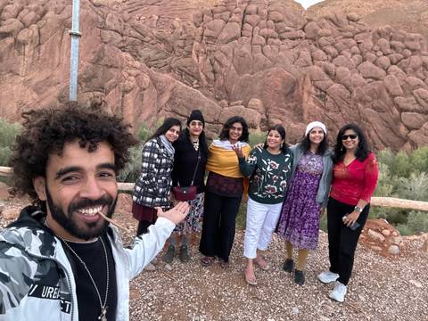 Smiling people taking a group photo in rocky terrain.