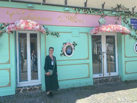 Person standing in front of a colorful storefront.