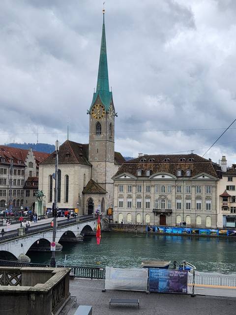 Spire of a church by a river in a city.