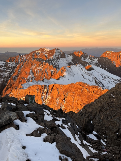 Sunlit mountains with snow patches creating a dramatic landscape.