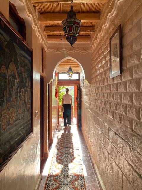       Person in a traditional hallway with bright light.
  