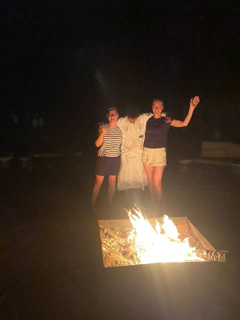       Group of people celebrating by a campfire.
  