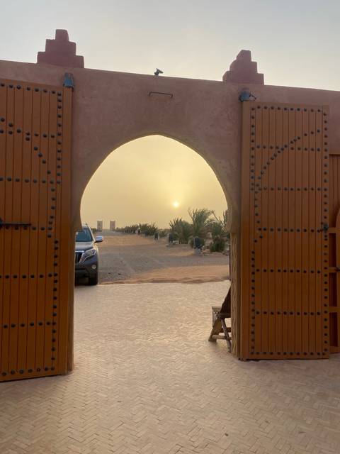       View through a traditional gate with a desert backdrop.
  