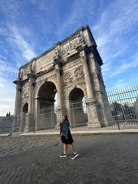 A person in front of the Arch of Constantine.