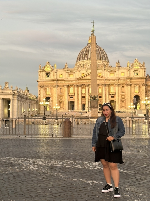 A person posing in front of St. Peter's Basilica.