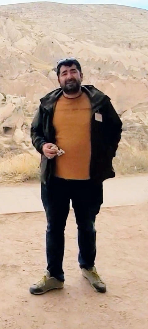 A person standing outdoors, dressed warmly, holding an item in hand.