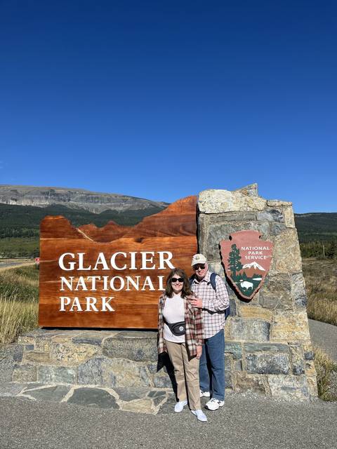 Two people posing by the Glacier National Park sign.