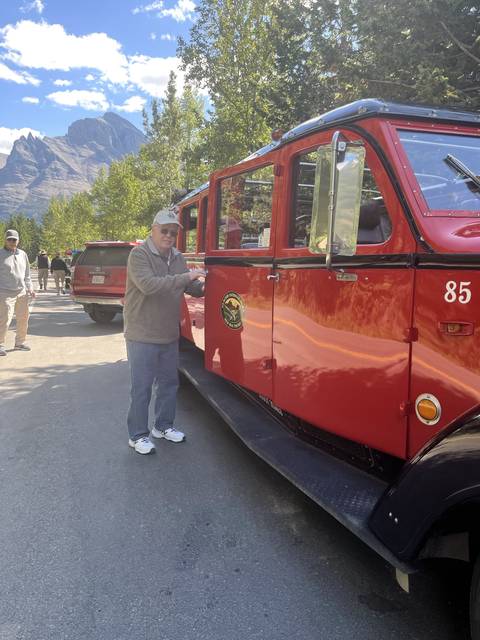       A person posing next to a classic red bus.
  