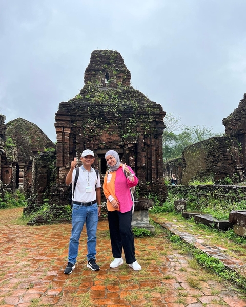 Two people standing in front of ancient ruined structure.