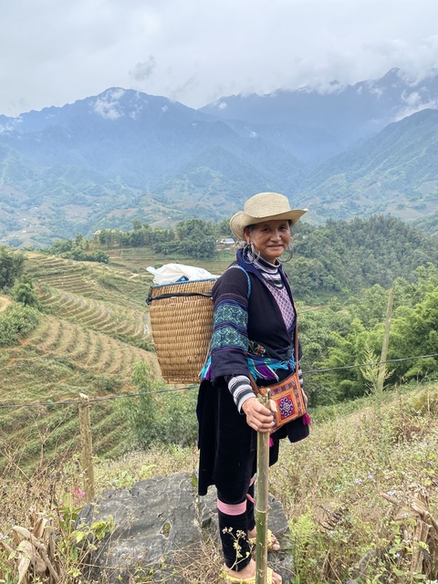 Person with traditional attire and basket in mountain setting.