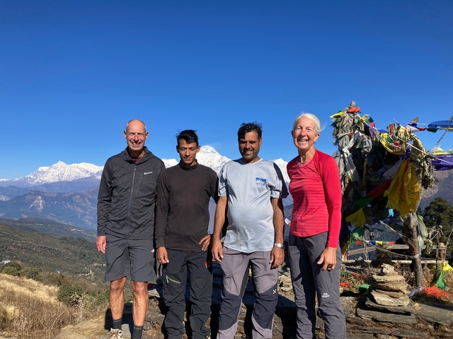 Group of people posing in front of snowy mountains.