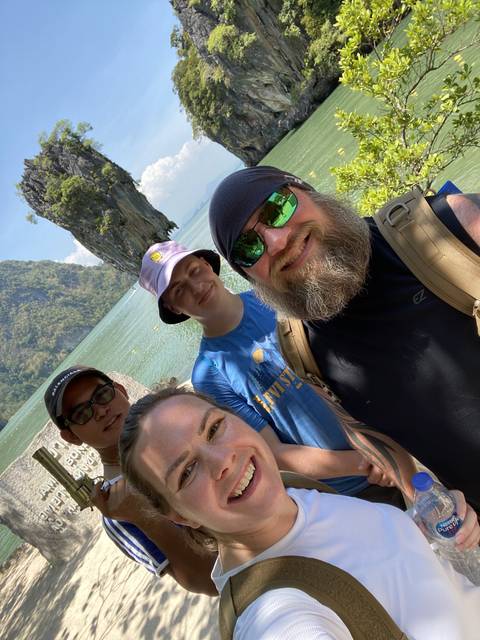       Group selfie with a scenic water background.
  