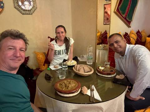 Three people dining, enjoying Moroccan dishes.